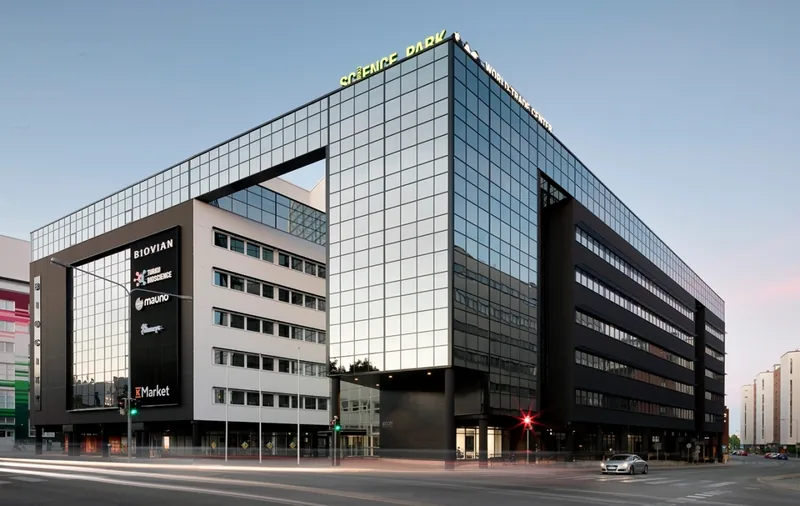 BioCity at dusk: a large glass and dark-panelled office building on a street corner, seen from the Tykistökatu–Lemminkäisenkatu junction.